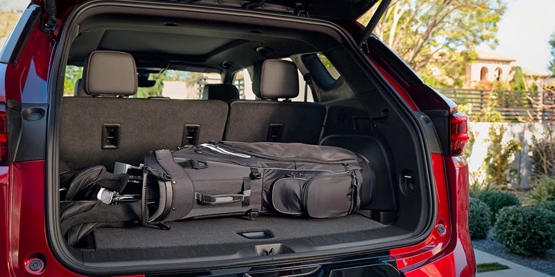 The trunk of a red 2024 Honda Pilot filled with luggage.