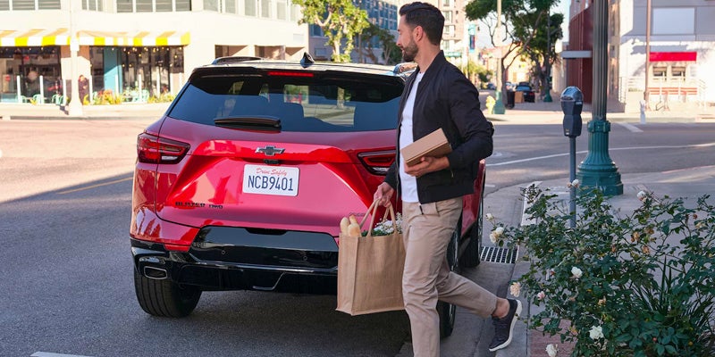 A man walks down the street carrying a shopping bag in his right hand.